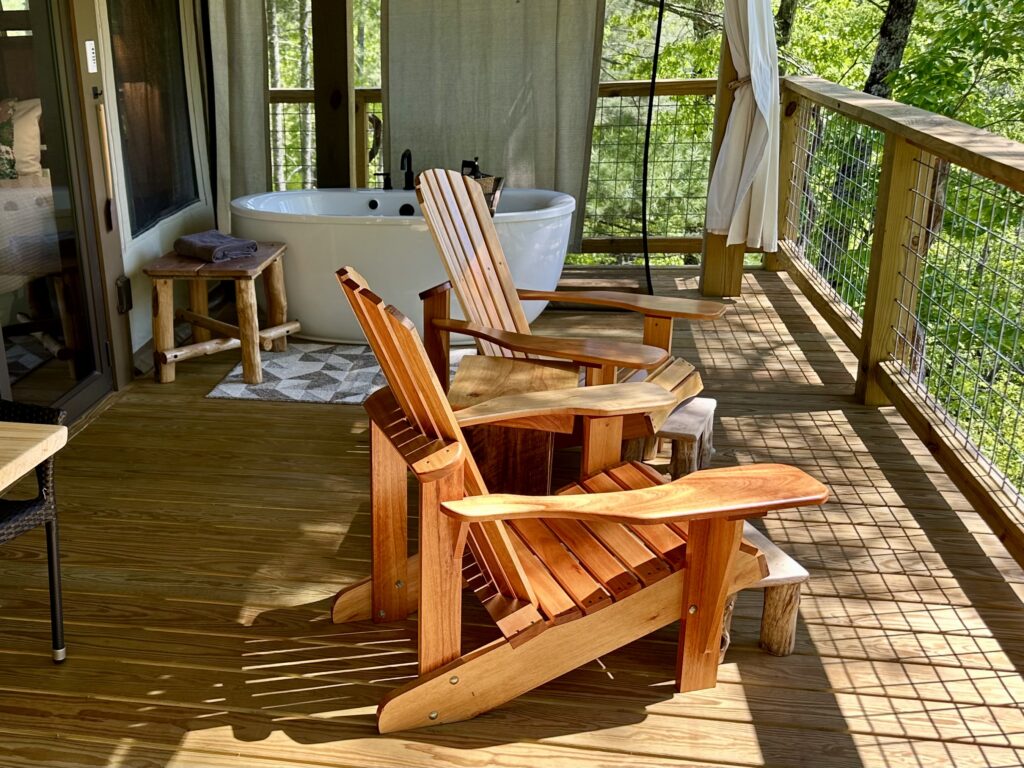 Outdoor heated bathtub with two Adirondack chairs at the Tuxedo Falls luxury glamping site in western NC
