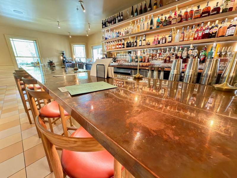 The sleek, copper bar inside next to the restaurant in the  clubhouse at The Stonebreaker Hotel in Fayetteville, Arkansas, featuring a premium selection of bourbon and spirits.
