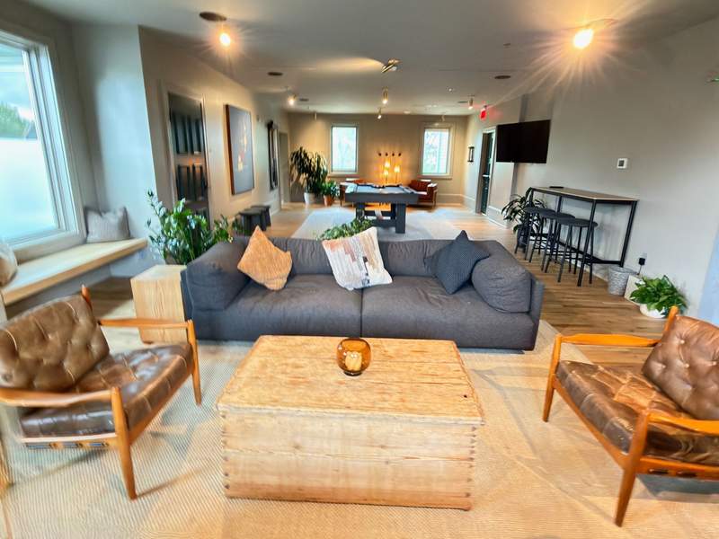 The upscale interior of the private, members-only clubhouse at The Stonebreaker Hotel, featuring a cozy bar, billiards table, and comfortable lounge seating with wooded views.