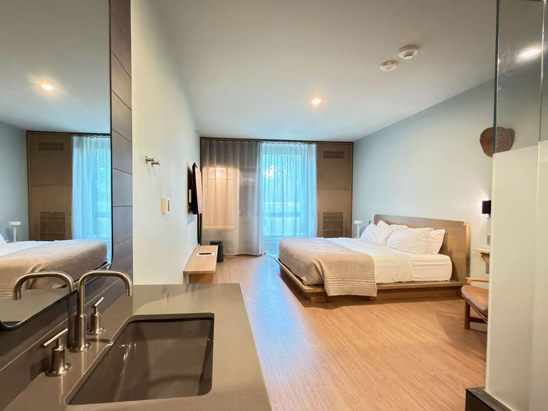 A standard guest room at The Stonebreaker Hotel showing a minimalist design, modern bedding, and a contemporary open-concept layout.