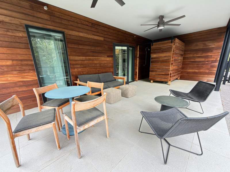 A private, shaded patio attached to a suite at The Stonebreaker Hotel, featuring an upscale outdoor shower surrounded by natural greenery.