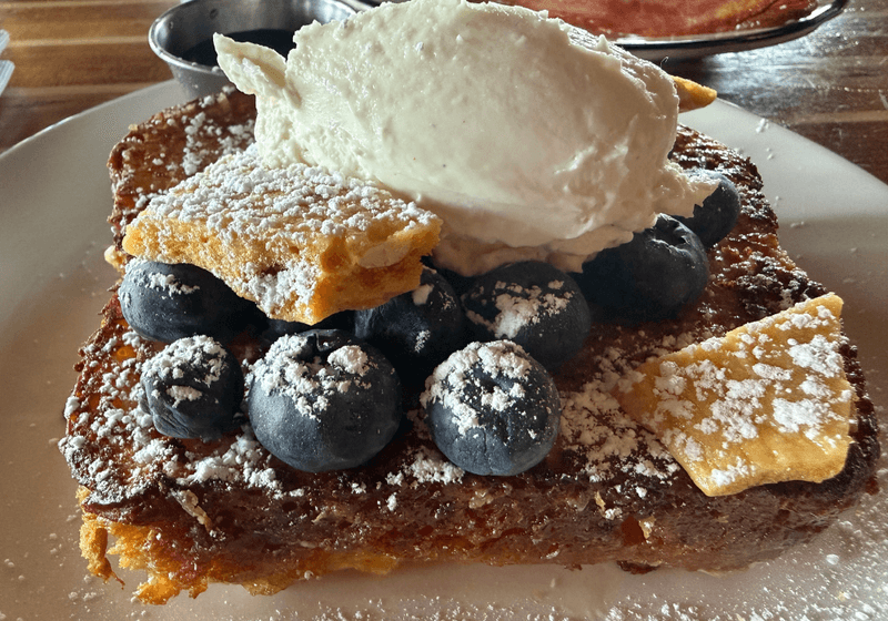 Thick slice of French toast topped with fresh blueberries, whipped cream, and powdered sugar at Automatic Seafood and Oysters in Birmingham, Alabama