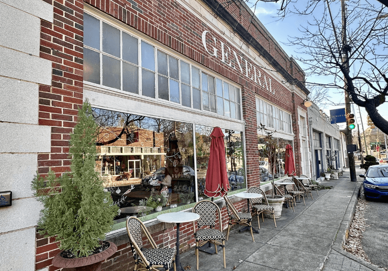 Exterior of The General restaurant with red brick facade, large windows, sidewalk cafe seating, and potted evergreen trees in Birmingham, Alabama
