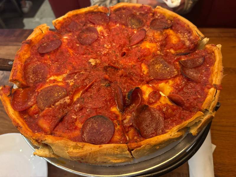 Classic Chicago deep dish pizza at Giordano's, showing a thick, cheesy slice with rich tomato sauce and golden crust on a plate, highlighting the iconic style of Chicago pizza.