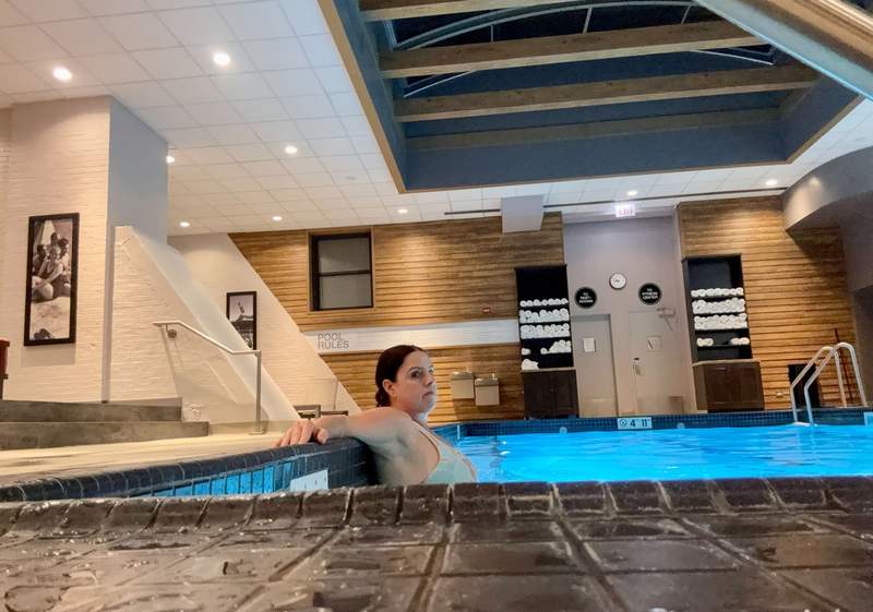 Person relaxing in the indoor pool at the Palmer House Hilton, featuring a calm, inviting swimming area with warm lighting and a comfortable, resort-like atmosphere.