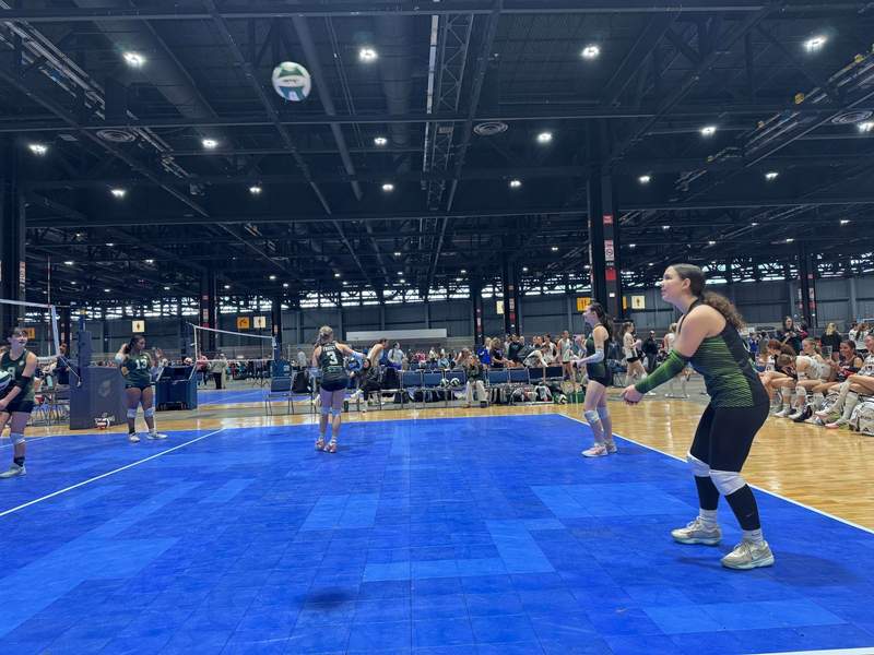 My daughter and her team competing in a volleyball tournament at McCormick Place on the court inside a large convention hall.