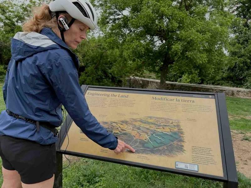 Guide Teresa pointing to display sign along the Mission Trail.