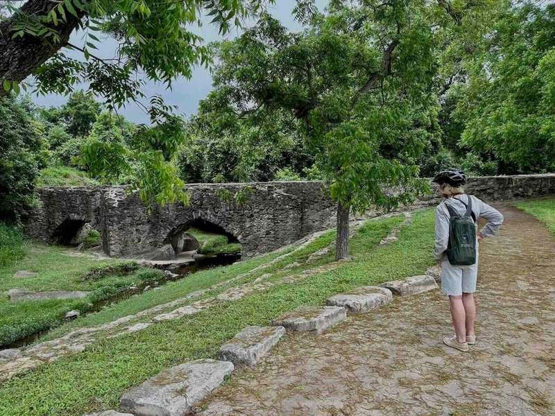 Stone aqueduct with water flowing through it, surrounded by trees