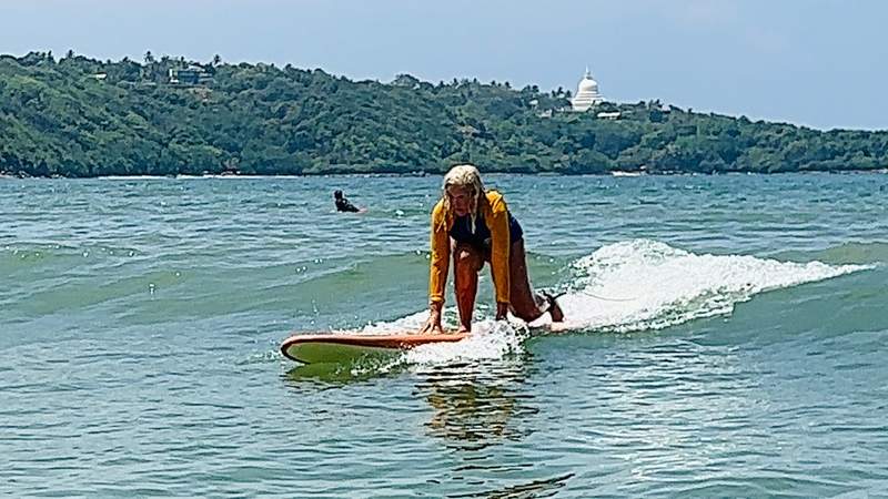 woman learning to surf in ocean waves.