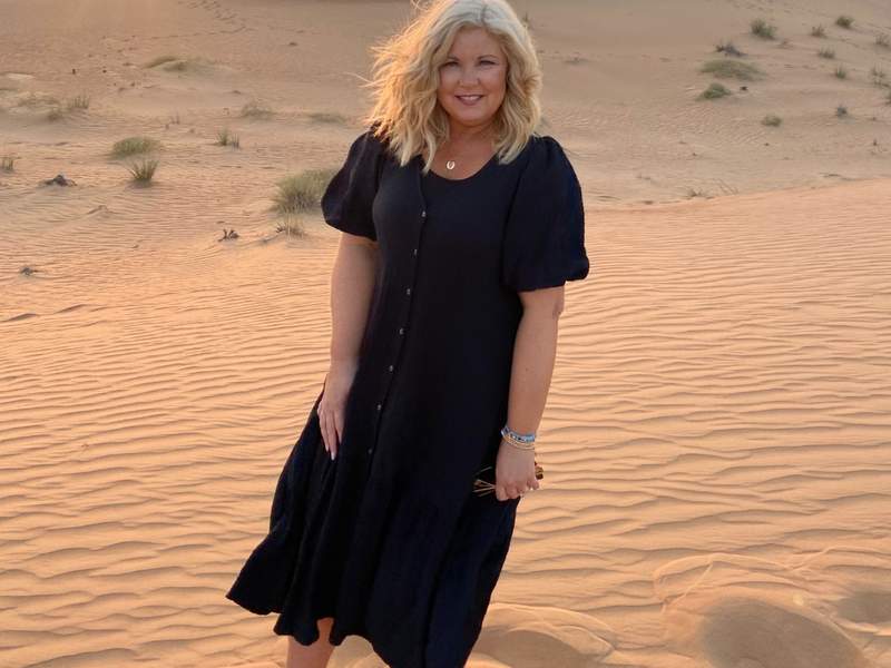 woman standing on sand dune in Dubai desert.