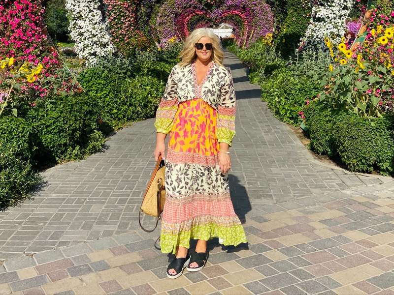 a woman standing in front of colorful flower displays.