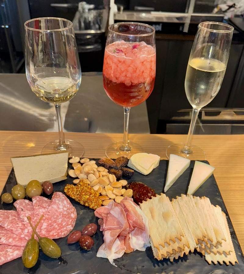 Beautiful charcuterie board with salame, olives, spanish almonds, cheese and crackers flaked by a flight of wine and prosecco.