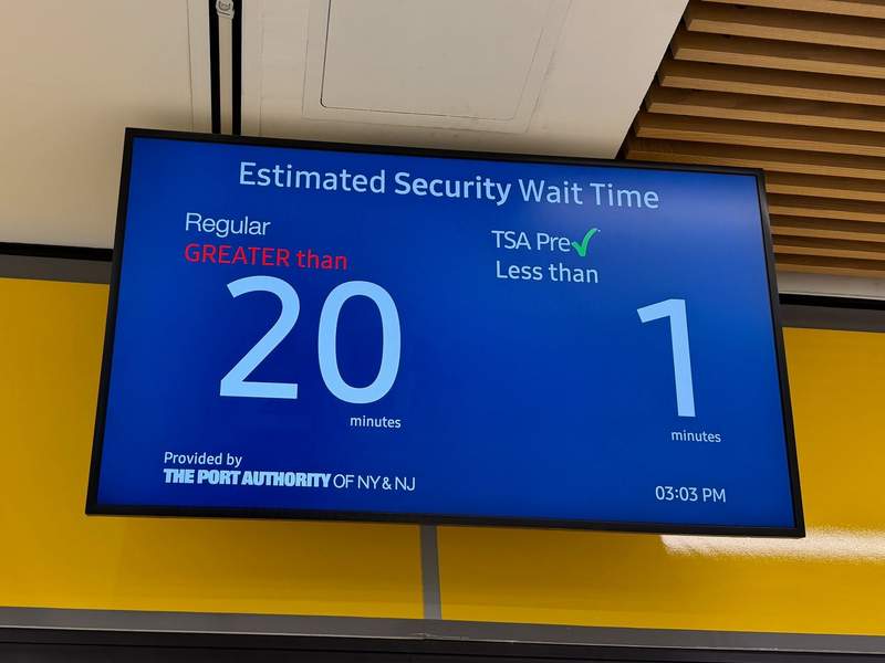 Blue sign with wait time for TSA security line. 