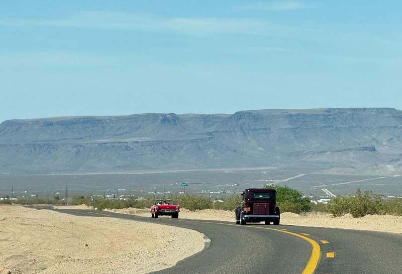 Mountains and a road with vintage automobiles