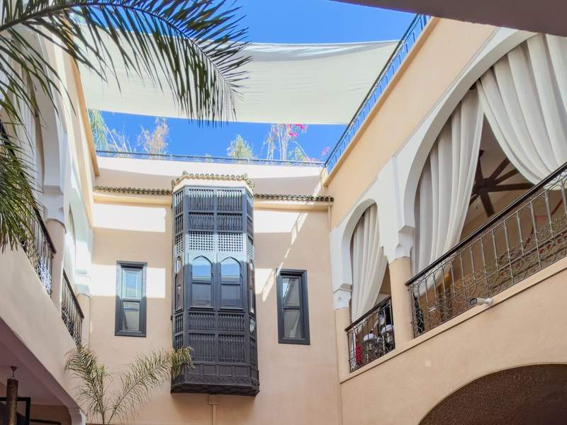 A building with a balcony and palm trees in a riad-style building in Marrakech.