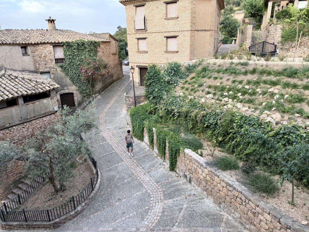 Medieval stone buildings line stone path with a solitary backpacker