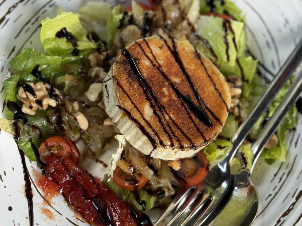 Balsamic drizzle on cheese wheel atop a salad at Asador Fiscal in Aragon