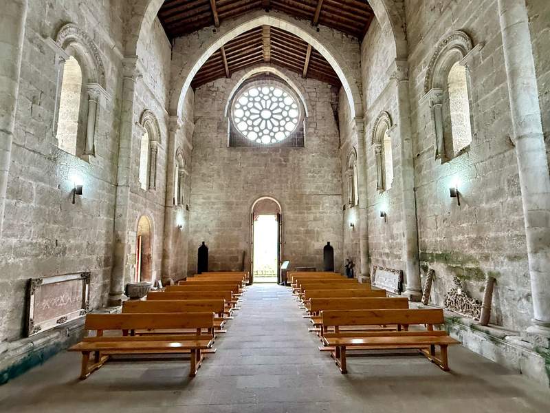 Rows of wooden pews inside a Romanesque church in Galicia, Spain.