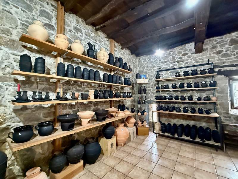 Stone-walled shelves lined with handcrafted black ceramic pots.