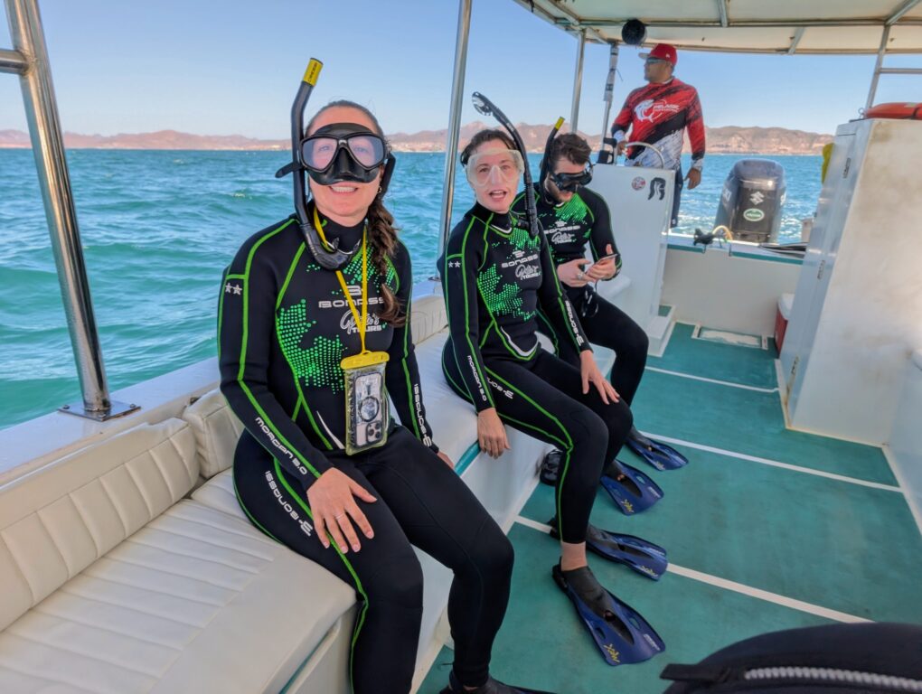 3 people in wet suits, snorkels and masks getting ready to swim with whale sharks in La Paz, Mexico