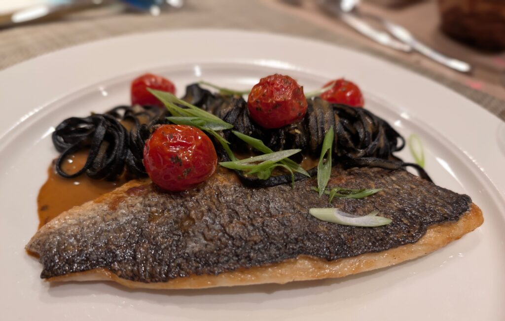 Fish dinner with black pasta and tomatoes