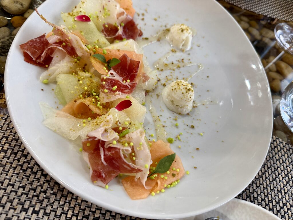 White plate with thinly sliced melon and ham at a restaurant in Alquezar, Spain.