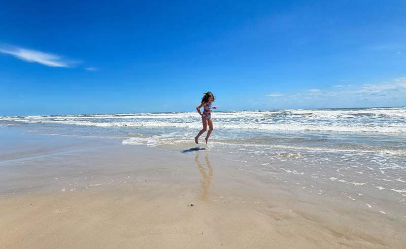 A young girl playing in the waves along a sandy beach 