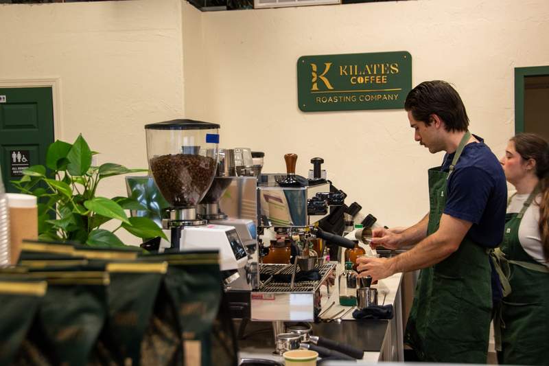A male barista making a coffee at the espresso machine 