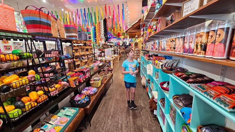 A girl shopping in a very colorful artist store that reflects the Mexican culture of sewing design 