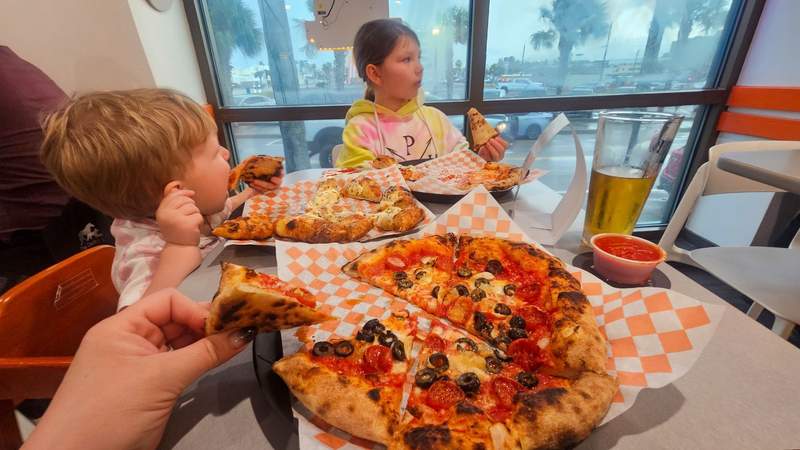 Two kids eating pizza while looking away from the camera 