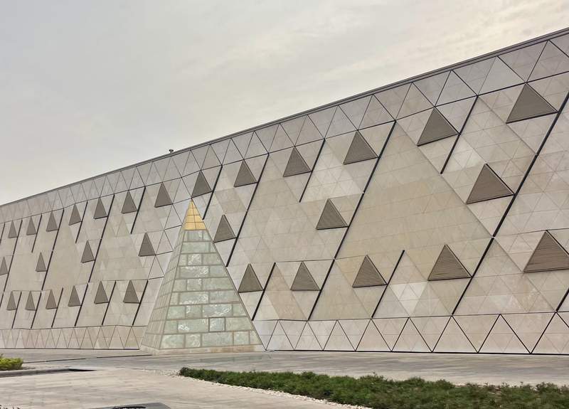The grand, modern exterior architecture of the Grand Egyptian Museum building located near the Giza Plateau.