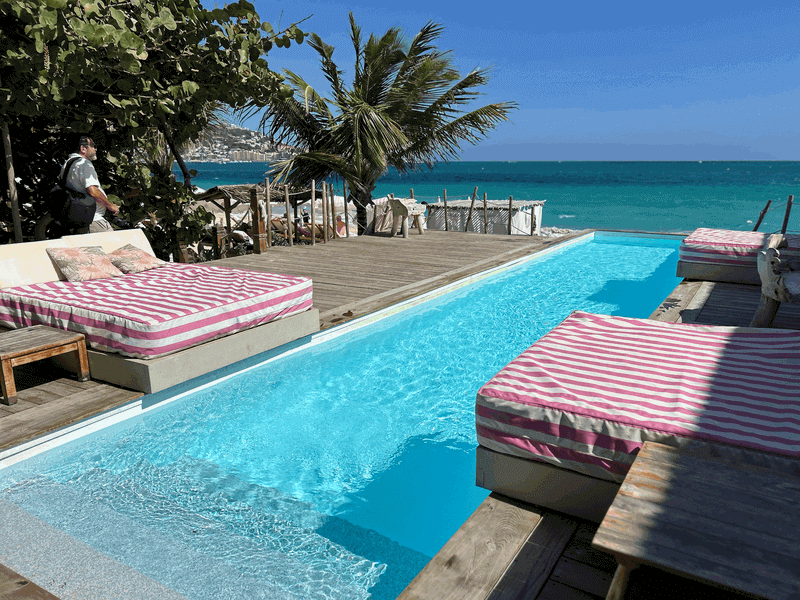 A luxurious, chic pool deck at Babacool Beach Club with upscale daybeds and private plunge pools overlooking the beach.