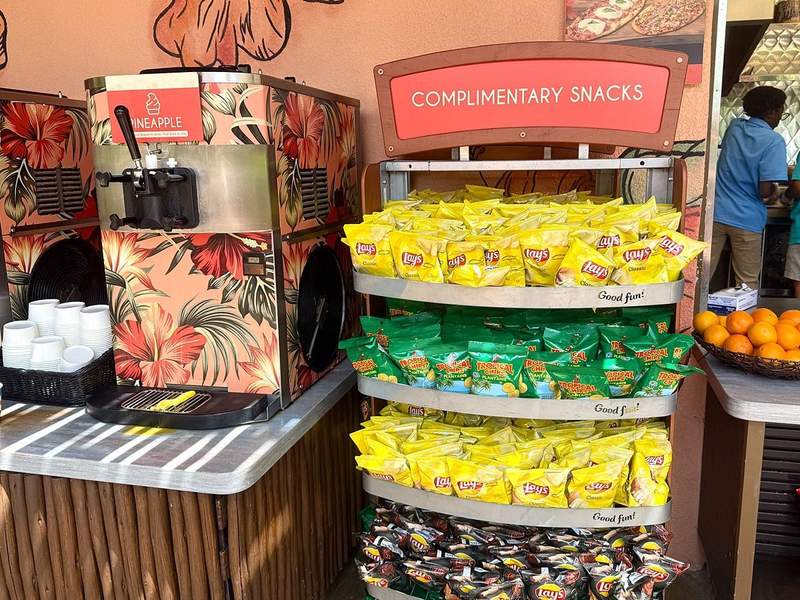 A rack with chips in between a tray of oranges and an ice cream machine