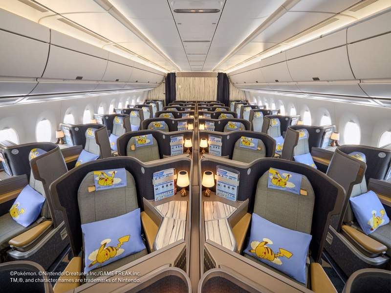 The Business Class cabin with large pod-like seats with a Pikachu headrest cover and a Pikachu pillow