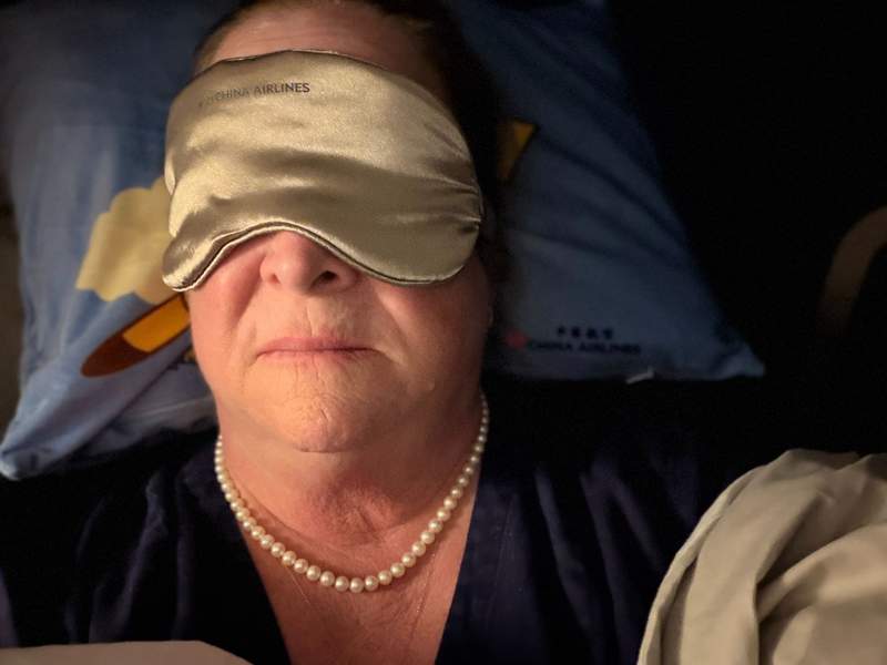 Alt Text: Lady sleeping with an eye mask and wearing pearls.