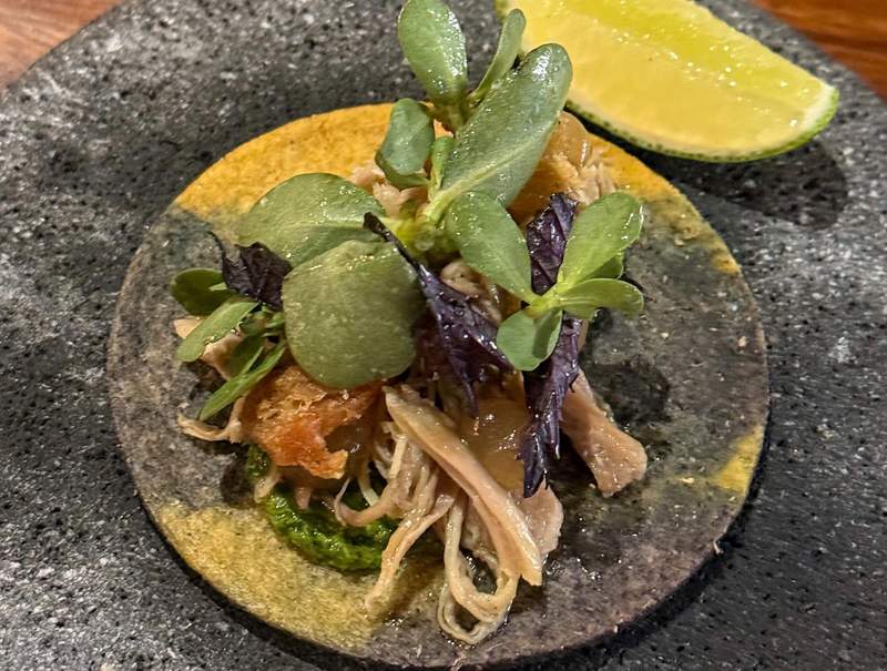 A gourmet pork tostada meticulously prepared and styled on an elegant plate at Xal restaurant by Chef Andoni Luis Aduriz.