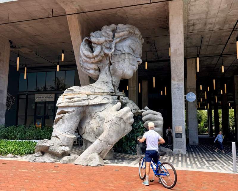 The Thrive sculpture by Daniel Popper, a giant 30-foot-tall public art piece depicting a stone figure opening its chest to reveal green plants, located on the Fort Lauderdale Riverwalk.