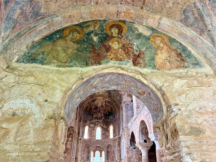 Byzantine church interior with stone walls, soaring chancel, arches and angel frescoes.