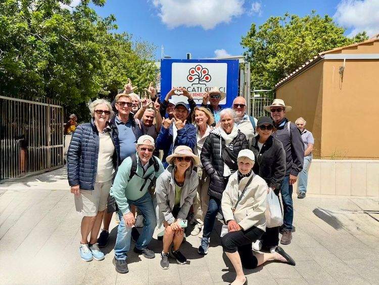 A small group of cruise guests gathered together and smiling alongside Chef Neil during a culinary market excursion in Cagliari.