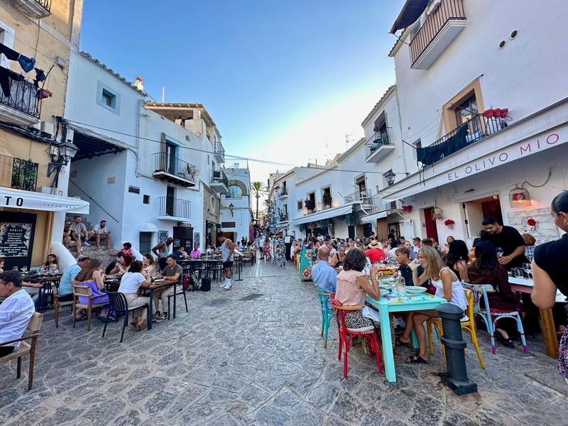 Stone paved street lined with cafes, shops and people enjoying themselves.