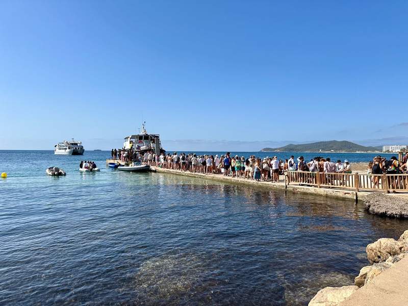 A line of people on a dock waiting to board a ship.