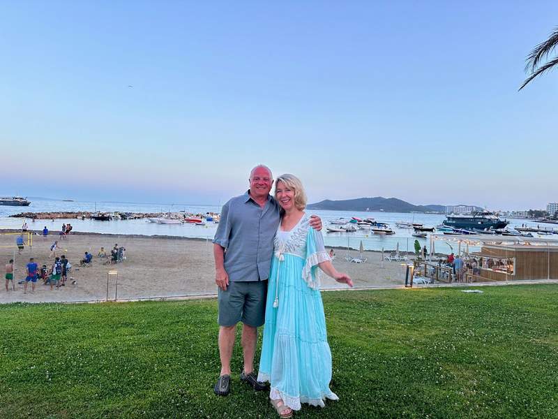 Author and husband posing in the grass in front of the beach and coast. 