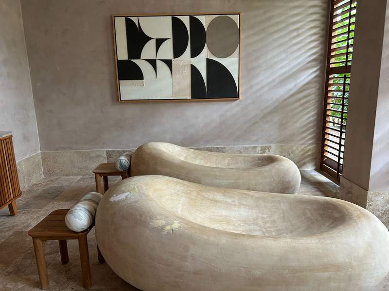 Two sculptural stone daybeds in the relaxation area of Alma Spa, positioned beneath a modern abstract artwork.