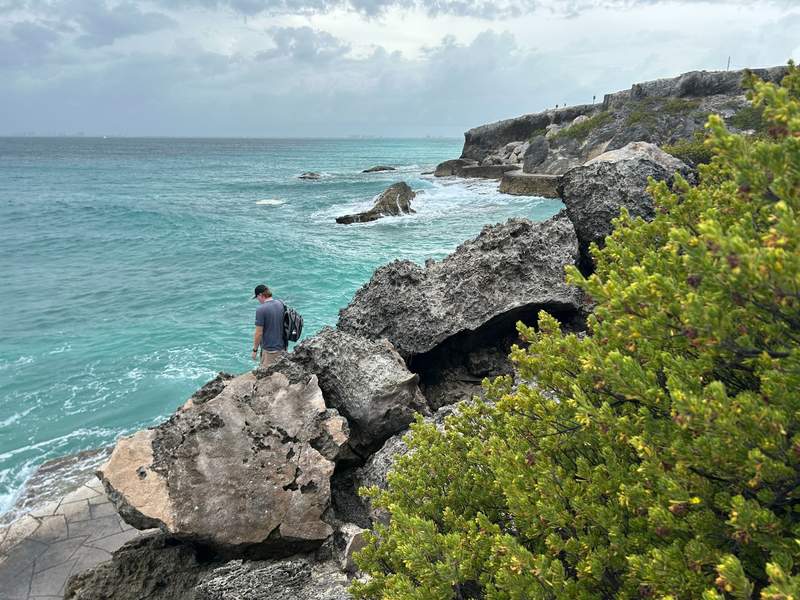 A man looks down on the turquoise waters of Punta Sur, where rugged limestone cliffs meet the Caribbean Sea on Isla Mujeres.