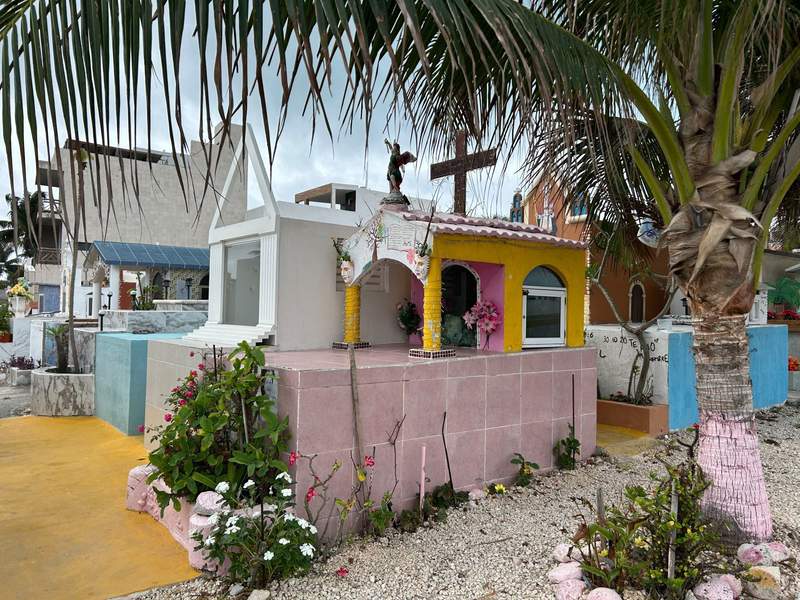 Colorful raised graves are surrounded by palm trees and flowers at the Sea-View Cemetery on Isla Mujeres.