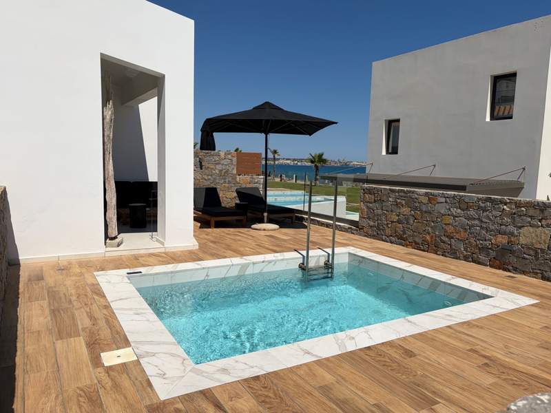 A wooden patio with a personal pool with stone diving walls separating it from the next resort unit.