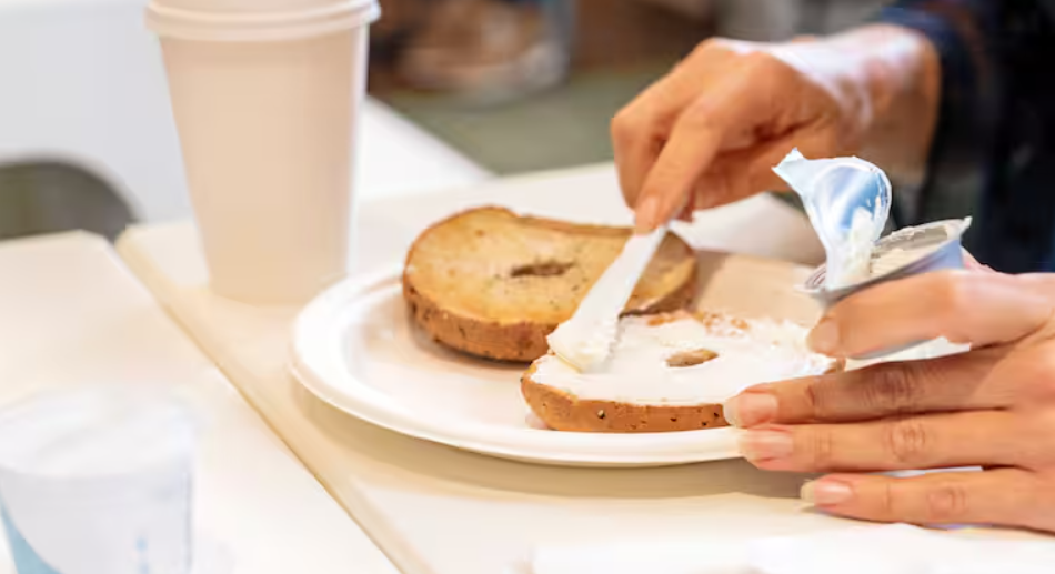 A woman spreading cream cheese on a bagel