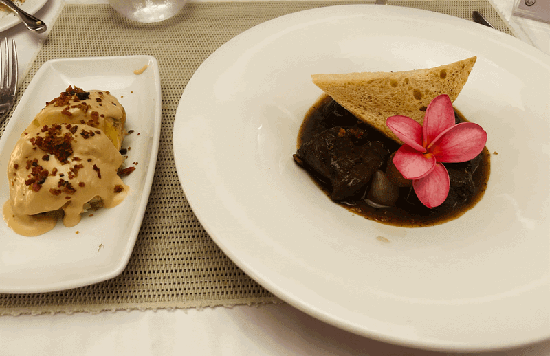 A gourmet plate of classic French Beef Bourguignon served alongside creamy, piped Duchess potatoes under soft restaurant lighting.