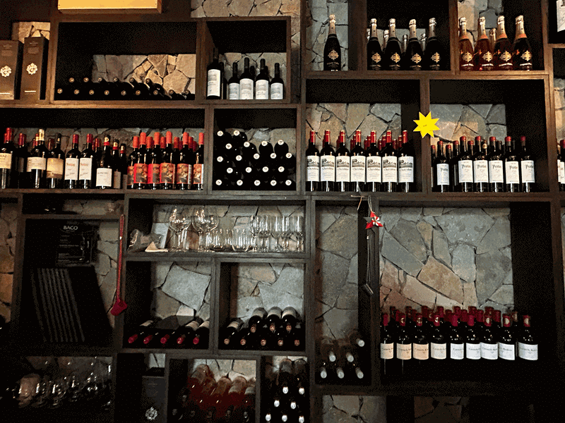 A well-lit, sophisticated wine cellar with rows of premium wine bottles displayed on wooden racks.