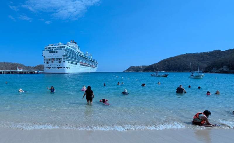 The Island Princess in the background with people wading into the ocean off a nearby beach